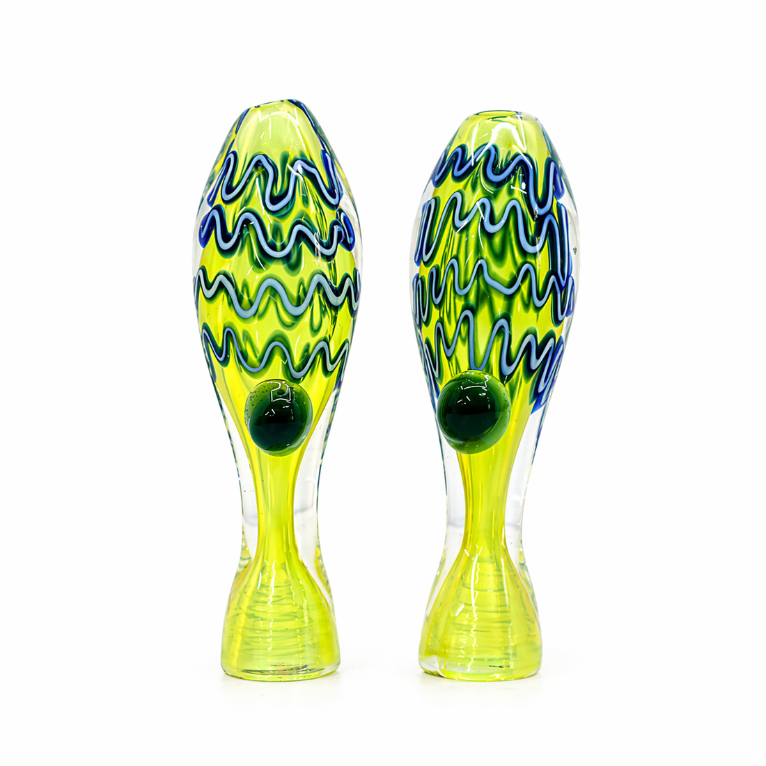 A pair of hand-blown glass fish-shaped ornaments with vibrant lime green bodies, blue and green wavy patterns, and dark green glass eyes, set against a plain white background.

