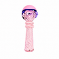 A pink glass baby teether or rattle with a textured spiral handle and a pink top featuring purple accents, isolated on a white background.


