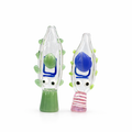Two hand-blown glass novelty figures shaped like cartoon fish or tadpole-like creatures, one with a green body and blue mouth area, and the other with a blue mouth area and pink striped neck, photographed on a white background.

