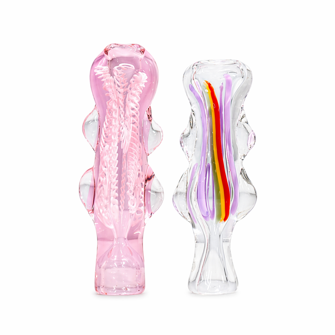 Two sculptural glass objects on a white background: a translucent pink glass piece on the left and a clear glass piece on the right with vertical purple, yellow, and orange inclusions.
